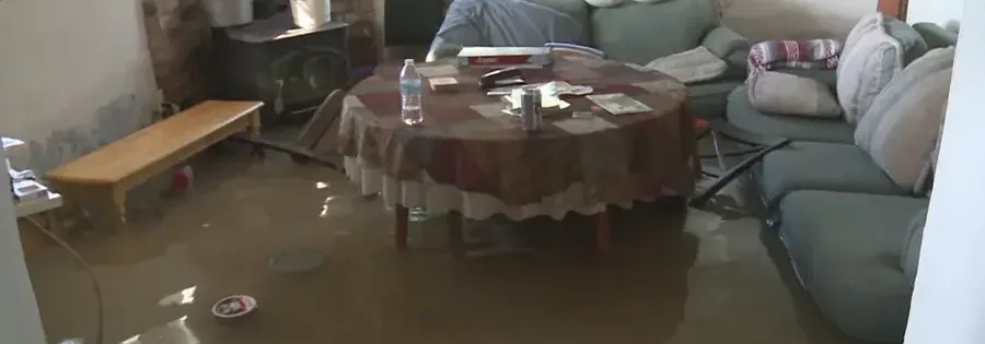 Standing water covers the floor around furnishings in a residential living room interior
