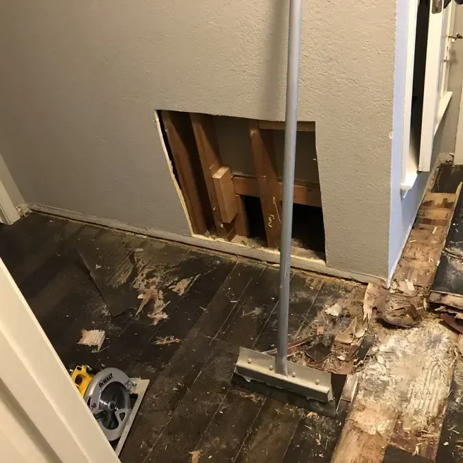 Removed flooring and an opened lower wall expose a room for drying work